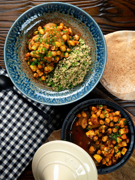 Overhead chickpea tagine with courgettes, harissa, and preserved lemons served with couscous.