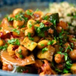 Close-up chickpea tagine with courgettes, harissa, almonds and preserved lemons.