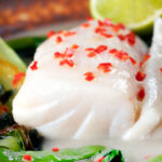 Close-up cod loin poached in coconut milk with fresh chilli.