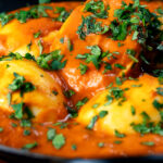 Close-up Indian inspired egg masala curry with fresh coriander.