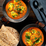 Overhead Indian inspired egg masala curry served with homemade chapatis.