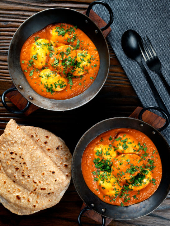 Overhead Indian inspired egg masala curry served with homemade chapatis.