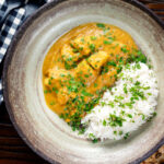 Overhead fruity pineapple and chicken curry with rice, coriander and naan.