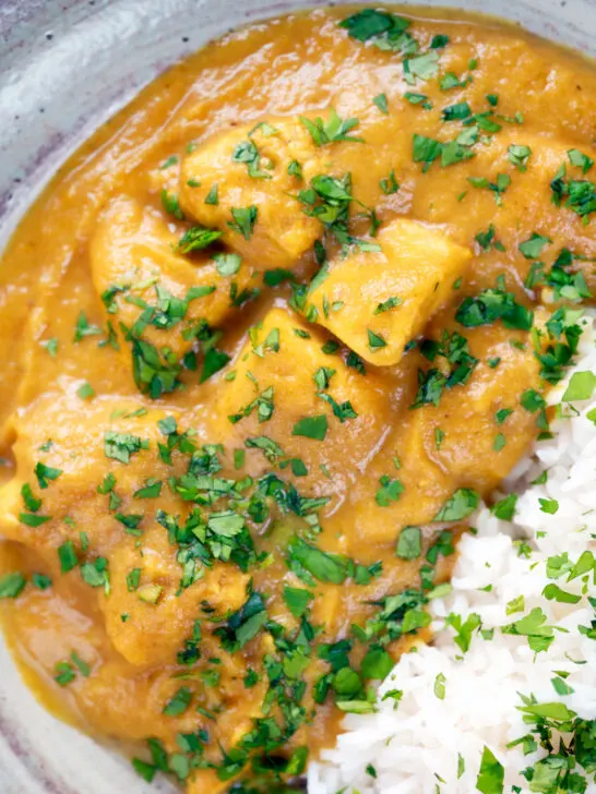 Overhead, close-up fruity pineapple and chicken curry with rice, coriander and naan.