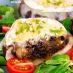 Goats cheese and caramelised onion stuffed mushrooms cut open to show filling featuring a title overlay.