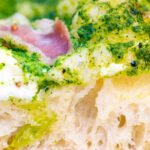 Close up section of the overnight crust on a goat cheese and pesto pizza.