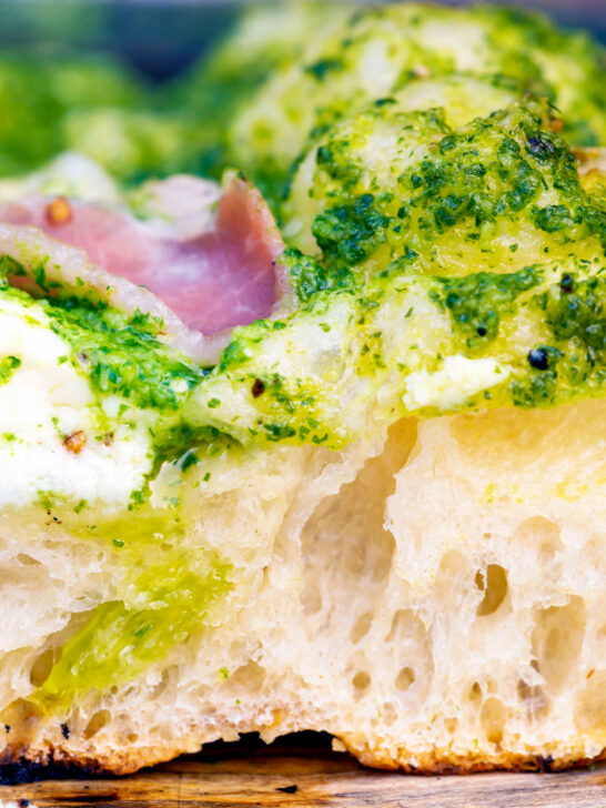 Close up section of the overnight crust on a goat cheese and pesto pizza.