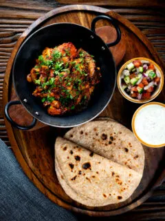 Overhead spicy halloumi curry served with chapatis, mint raita and kachumber salad.