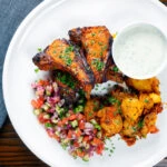 Overhead tandoori lamb chops with roasted Bombay potatoes, raita and kachumber salad.