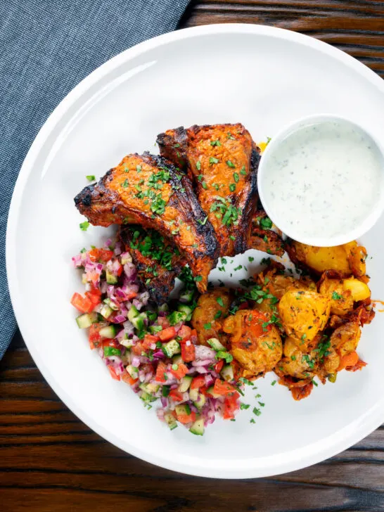 Overhead tandoori lamb chops with roasted Bombay potatoes, raita and kachumber salad.