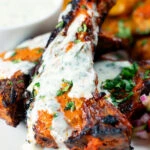 Close-up Tandoori lamb chops with minted yoghurt raita.