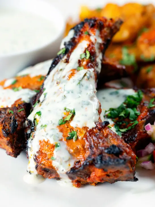 Close-up Tandoori lamb chops with minted yoghurt raita.