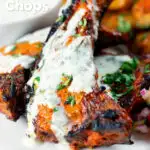 Close-up Tandoori lamb chops with minted yoghurt raita, featuring a title overlay.