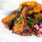 Tandoori lamb chops with roasted Bombay potatoes, raita and kachumber salad.