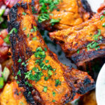 Overhead close-up grilled tandoori lamb chops with roasted Bombay potatoes.