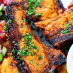 Overhead close-up grilled tandoori lamb chops with roasted Bombay potatoes.