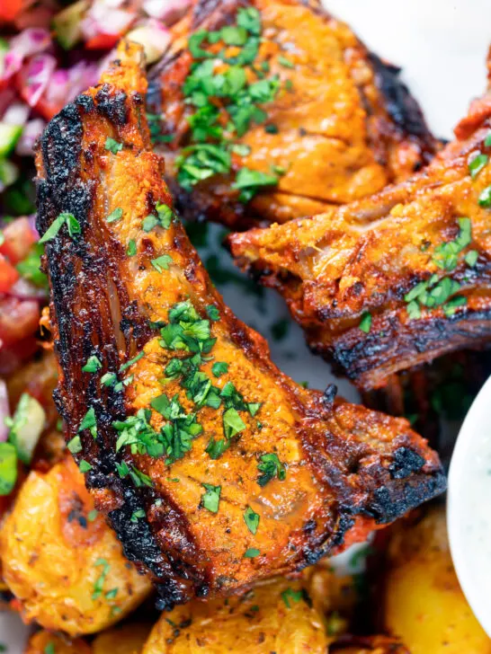 Overhead close-up grilled tandoori lamb chops with roasted Bombay potatoes.