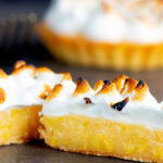 Individual lemon meringue pie with Italian meringue cut open to show filling.