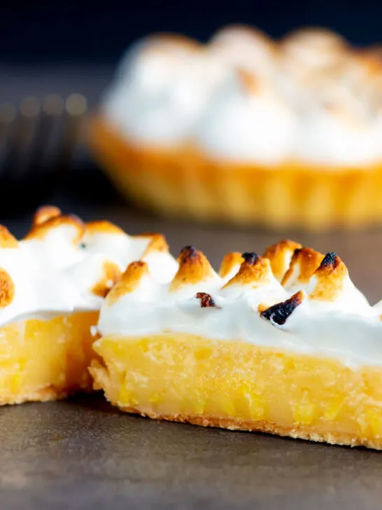 Individual lemon meringue pie with Italian meringue cut open to show filling.