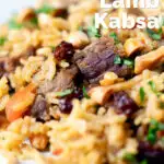 Close-up lamb kabsa, Saudi Arabian rice with almonds and raisins featuring a title overlay.
