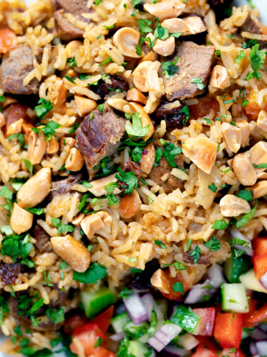 Overhead close-up lamb kabsa, Saudi Arabian rice with almonds and raisins.