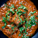 Overhead close-up lamb madras curry fakeaway with fresh coriander.