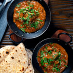 Overhead lamb madras curry fakeaway served with homemade chapatis.