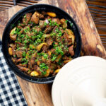 Overhead Moroccan lamb tagine with dates and almonds served in a tagine.