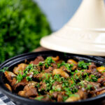 Moroccan lamb tagine with dates and almonds served in a traditional cooking pot.