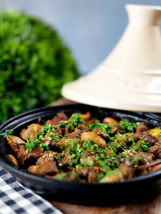 Moroccan lamb tagine with dates and almonds served in a traditional cooking pot.