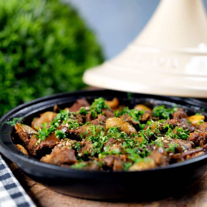 Moroccan influenced lamb tagine with dates and almonds presented in a traditional pot.
