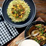 Overhead Moroccan lamb tagine served on a plate with buttered couscous.