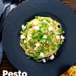 Overhead pesto pasta with aged goat cheese and peas served with garlic bread featuring a title overlay.