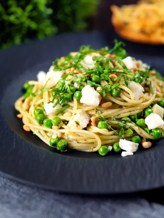 Pesto pasta with aged goat cheese and peas served with garlic bread.