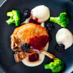 Overhead pork chops with a cider and fresh blackberry sauce with Jerusalem artichoke puree.