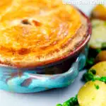 Close-up rabbit pot pie with a suet crust served with buttery potatoes and peas featuring a title overlay.