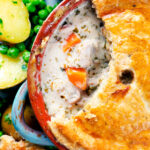 Overhead close up rabbit pot pie with a suet crust cut open to show creamy filling.