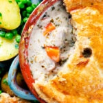 Overhead close up rabbit pot pie with a suet crust cut open to show creamy filling.