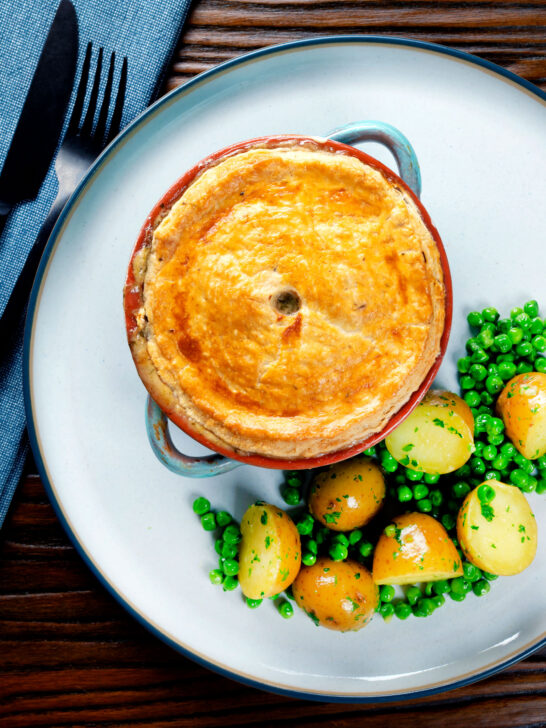 Overhead rabbit pot pie with a suet crust served with buttery potatoes and peas.