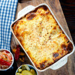 Overhead Hungarian layered potato bake, rakott krumpli served with pickles.