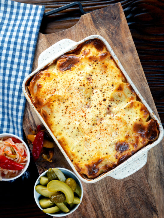 Overhead Hungarian layered potato bake, rakott krumpli served with pickles.