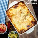 Overhead Hungarian layered potato bake, rakott krumpli served with pickles featuring a title overlay.