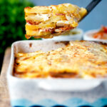 Spoon of potato bake being take out of a bowl of Hungarian rakott krumpli.