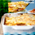 Spoon of potato bake being take out of a bowl of Hungarian rakott krumpli featuring a title overlay.