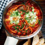 Overhead shakshuka, a baked tomato and egg stew with chorizo sausage.
