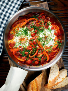 Overhead shakshuka, a baked tomato and egg stew with chorizo sausage.