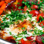 Close-up chorizo shakshuka a baked in a tomato sauce with egg, pepper and onion.