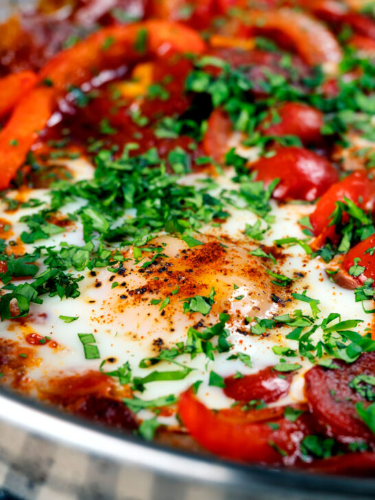 Close-up chorizo shakshuka a baked in a tomato sauce with egg, pepper and onion.