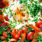 Overhead close-up shakshuka, a baked tomato and egg stew with chorizo sausage.