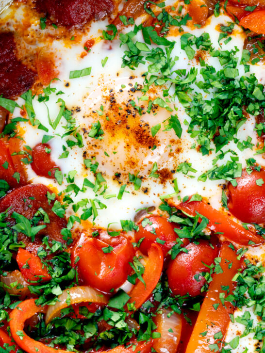 Overhead close-up shakshuka, a baked tomato and egg stew with chorizo sausage.